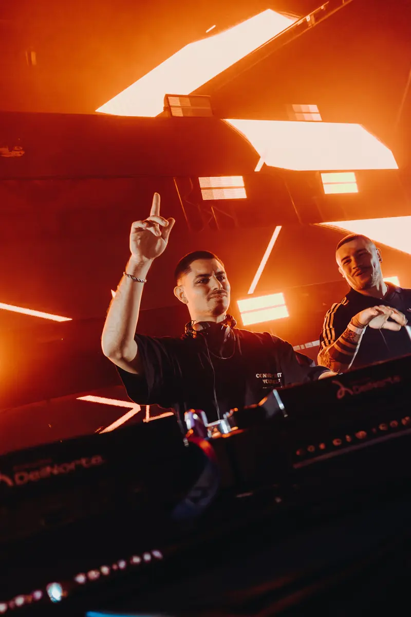 DJs en la cabina con luces rojas